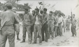 Las milicias fidelistas escoltan a un grupo de prisioneros cuyas manos aparecen...