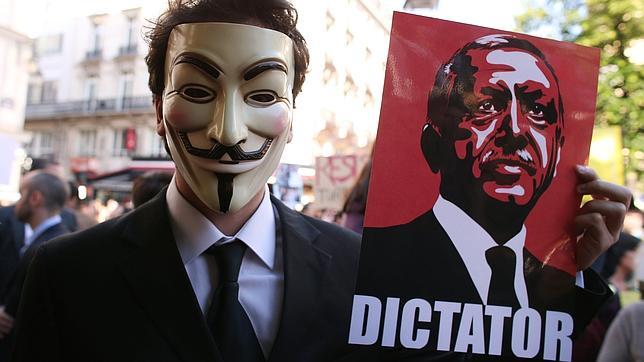 Un hombre se manifiesta con la pancarta de la imagen del primer ministro turco acusándolo de «dictador»