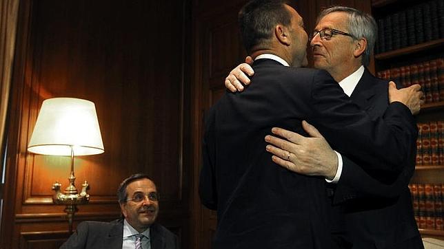 Juncker abraza al ministro de Finanzas heleno, Yannis Sturnaras, en presencia de Andonis Samaras