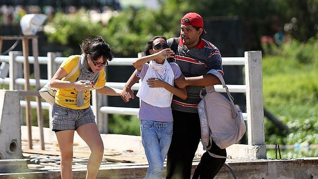Dos mujeres afectadas por gases lacrimógenos, ayudadas por un hombre, en la protesta contra el gasto público en la Copa Confederaciones, este miércoles en Fortalezaa policía enfrenta a un numeroso grupo de manifestantes que protestan contra el alto gasto público en la Copa Confederaciones hoy,