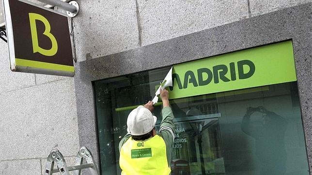 Un operario cambia el rótulo de una oficina de Caja Madrid por el de Bankia