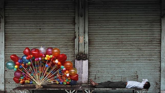 Un vendedor de globos echa una cabezada durante el ramadán en un barrio de Nueva Delhi