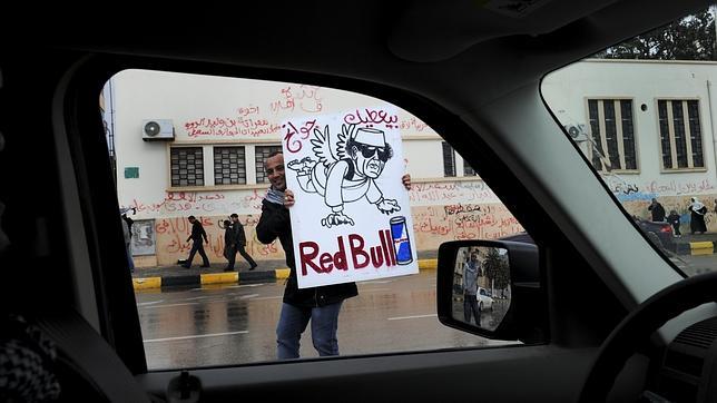 Un ciudadano muestra una caricatura de Gadafi en una calle de Bengasi