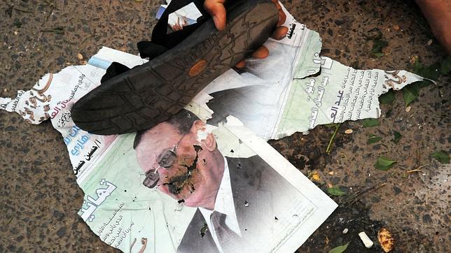 Un manifestante golpea con su zapato una imagen del depuesto dictador Saleh