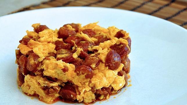 Un revuelto de huevos con chorizo, jamón y tocino, añadiendo a veces sesos de cordero