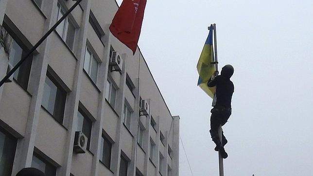 Un prorruso trepa por el asta para retirar la bandera ucraniana junto al Ayuntamiento de Mariúpol, el pasado domingo