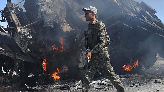 Un militar iraquí junto a un vehículo de la OTAN ardiendo tras un choque con talibanes en Jalalabad