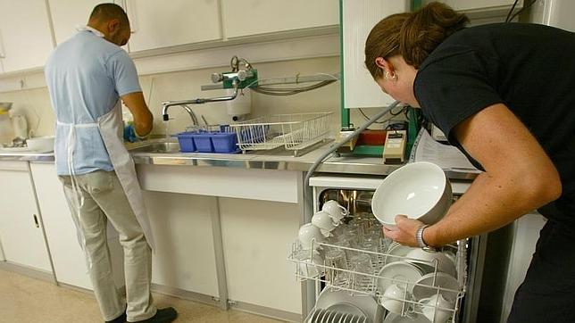 Una pareja llena el lavaplatos después de comer