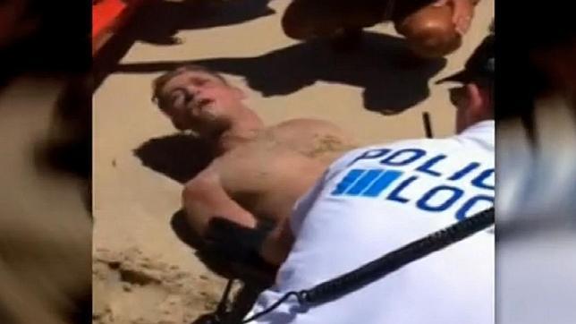 Un joven es reducido por los sanitarios en la playa de Magaluf