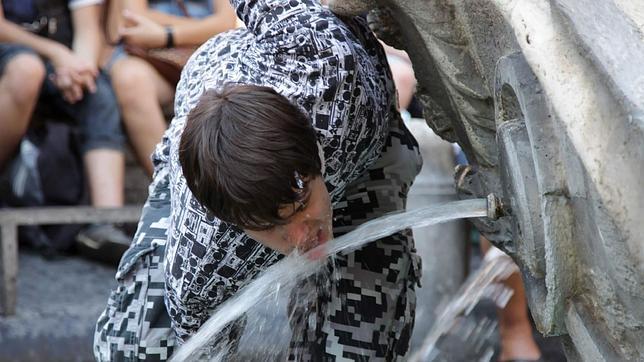 Un joven se refresca en una fuente