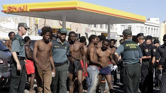 Un grupo de subsaharianos es custodiado por agentes de la Guardia Civil tras un salto en Melilla en 2012