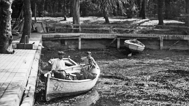 Un hombre y dos niños, montados en una barca en el estanque de El Retiro