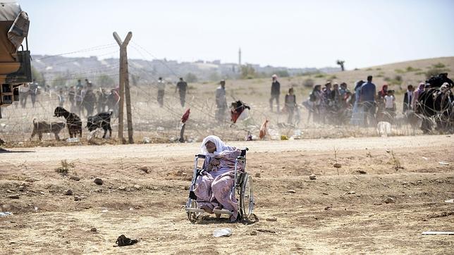 Refugiados kurdos abandonando Siria a través de una valla hacia territorio turco