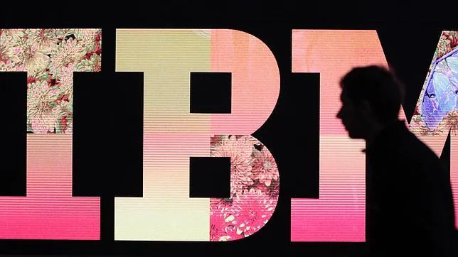 Un hombre pasa frente al logo de IBM
