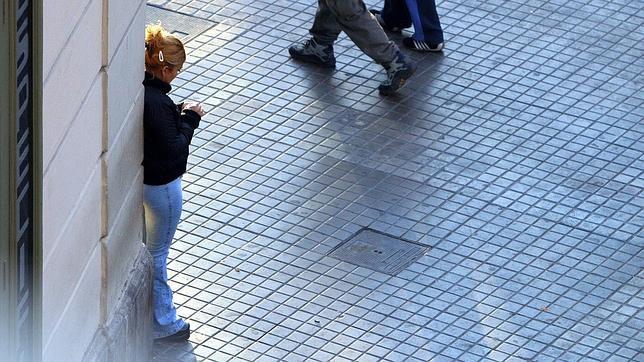 Una prostituta aguarda en una esquina a su próximo cliente en plena calle