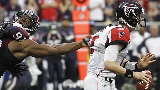 Matt Ryan (derecha), de los Atlanta Falcons, es agarrado por un rival