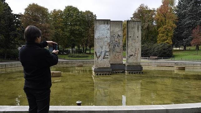 Una mujer hace una foto con su móvil con los restos del muro de Berlín, en el parque homónimo