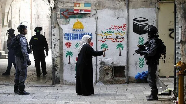Una mujer palestina se dirige a los agentes israelíes que patrullan la ciudad vieja de Jerusalén