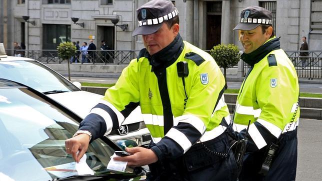 Agentes poniendo un aviso de sanción en el parabrisas de un vehículo