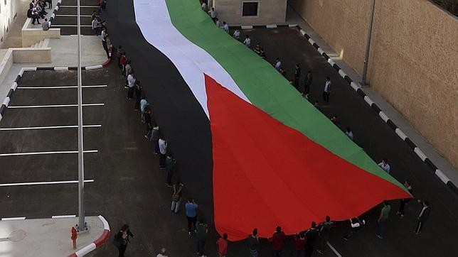 Decenas de personas despliegan una bandera palestina en Cisjordania