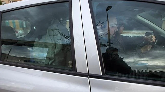 Uno de los detenidos este lunes por los presuntos abusos a un menor en Granada, en la parte trasera del coche, se tapa la cara