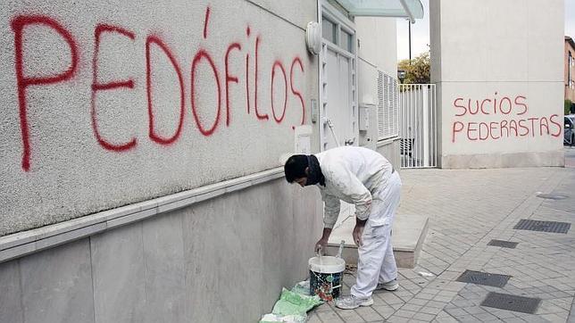 Un pintor comienza a repasar con pintura blanca una de las pintadas aparecidas en rojo esta mañana con acusaciones de pedofilia y pederastia en las paredes de la parroquia San Juan María Vianney de Granada
