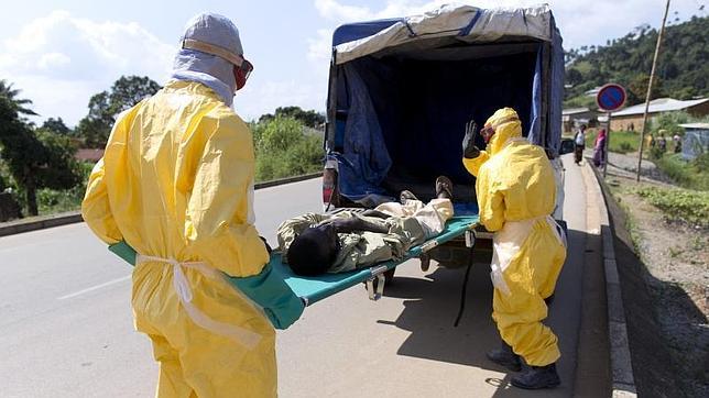 Dos sanitarios protegidos trasladan a un enfermo de ébola en Guinea Conakry a un centro de tratamiento