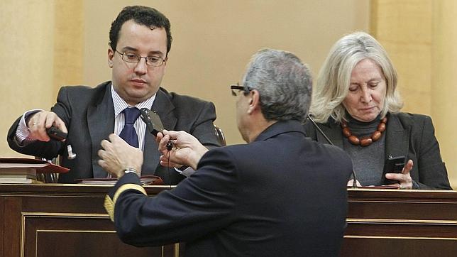 Un ujier entrega los equipos de traducción simultanea durante la intervención de Jordi Vilalbana (CIU)