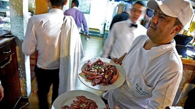 Un empleado muestra platos listos para servir en el restaurante «La Huerta», de Caracas