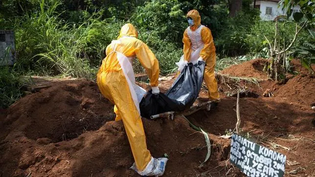 Dos trabajadores funerarios entierran el cadáver de una víctima del ébola en Sierra Leona