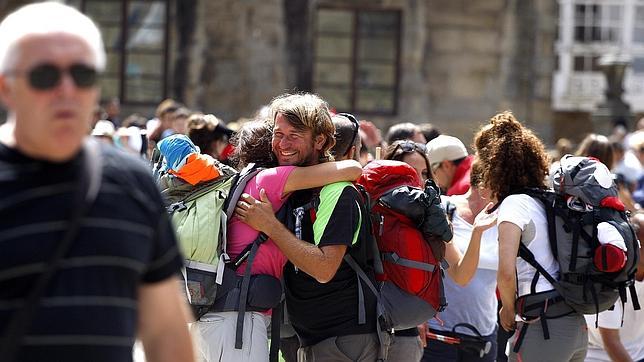 Varios peregrinos se abrazan gozosos en la plaza del Obradoiro