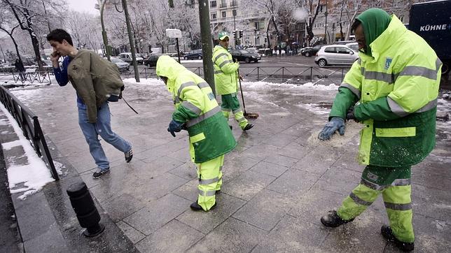 Varios operarios esparcen sal en una calle de Madrid