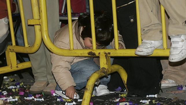 Un pequeño intenta recoger caramelos del suelo, al paso de las carrozas