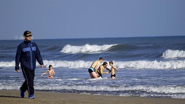 Un padre se baña con sus hijos el pasado 1 de enero en la playa de Las Arenas de Valencia donde a pesar del frío el cielo estaba despejado y lucía el sol