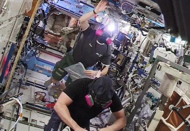 Los astronautas Barry Wilmore (al fondo) and Terry Virts entran en el segmento estadounidense de la ISS llevando máscaras de protección
