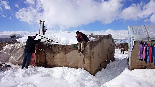 Un refugiado sirio intenta retirar la nieve del techo de su tienda en el campo de refugiados de Brital, al este del Líbano