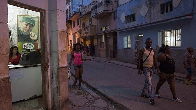 Unos viandantes pasan junto a una tienda de La Habana, con una imagen de Fidel Castro