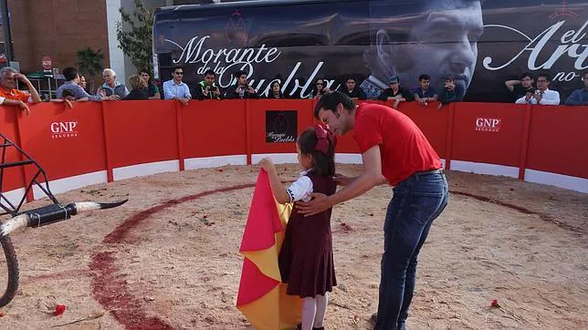 Una niña aprende a coger el capote en el ruedo móvil del Morante Tour