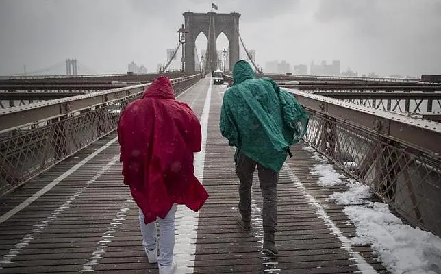 Dos turistas atraviesan el puente de Brooklyn en medio de una tormenta de nieve en Nueva York, Estados Unidos, este lunes