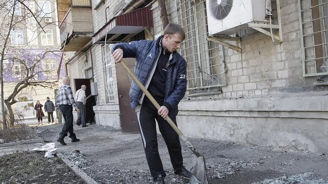Un vecino limpia los estragos de la guerra en la ciudad de Donetsk