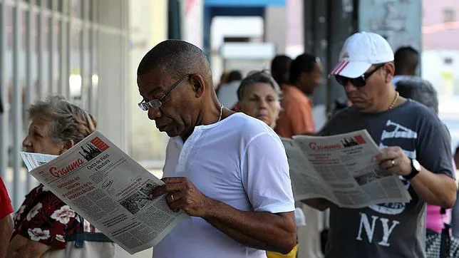 Dos hombres leen el último mensaje de Fidel Castro en el diario oficial «Granma», este martes en La Habana