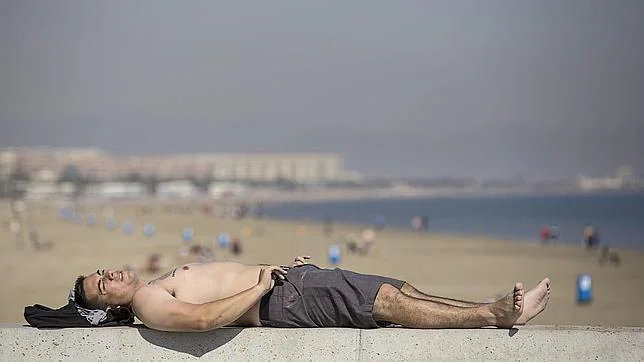 Un hombre toma el sol, este jueves, frente a la playa de Las Arenas de Valencia