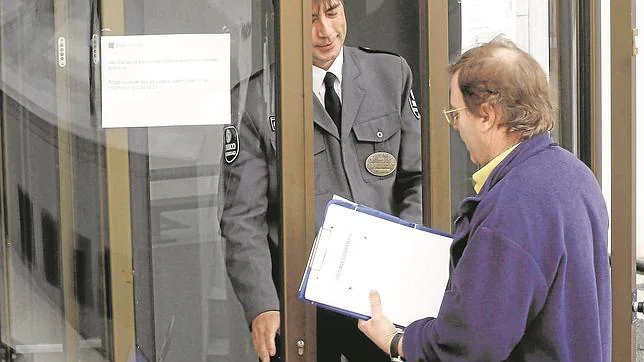 Un vigilante controla la entrada de clientes de Banco Madrid en la capital de España