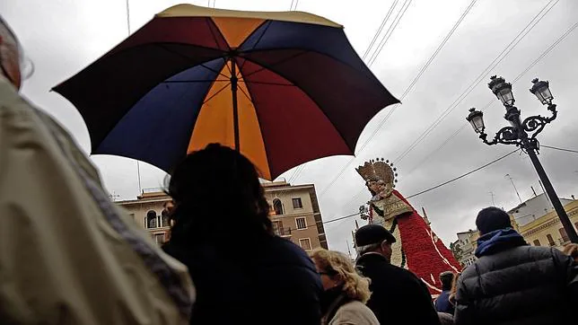 Varias personas se protegen de la lluvia en la plaza de la Virgen