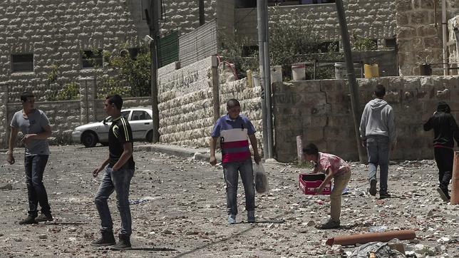 Adolescentes palestinos recogen latas tras los recientes enfrentamientos en el barrio de At-Tur, en Jerusalén Este
