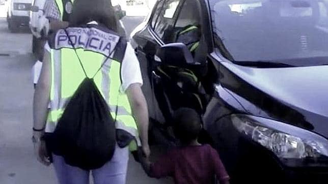 En la imagen, facilitada por la Policía Nacional, se ve a una de las agentes acompañando a uno de los menores