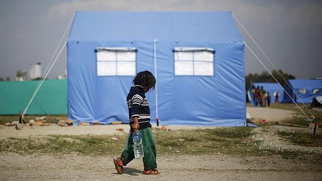 Víctima del terremoto lleva una botella de agua en un campamento para personas desplazadas, en Katmandú