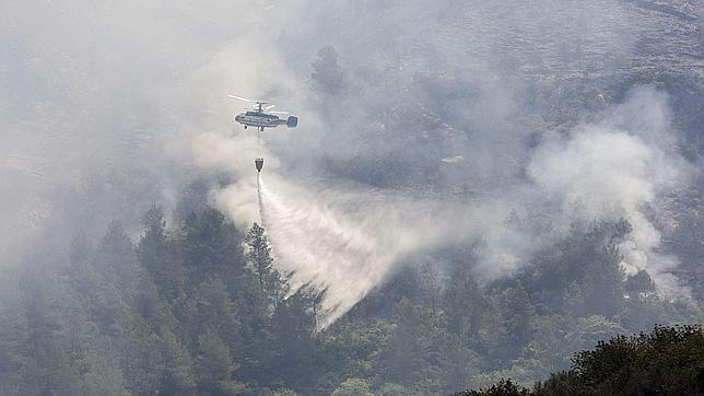 Un helicóptero refresca el terreno afectado por el incendio forestal en la provincia de Alicante