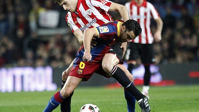 Xavi Hernández y Javi Martínez luchan por un balón dividido