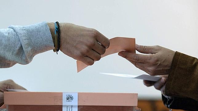 Un votante entrega su sobre con el voto en una mesa electoral